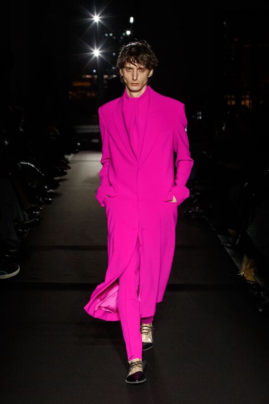 Яркий розовый костюм с длинным пиджаком и строгими линиями, привлекает внимание своей смелостью и современным стилем
