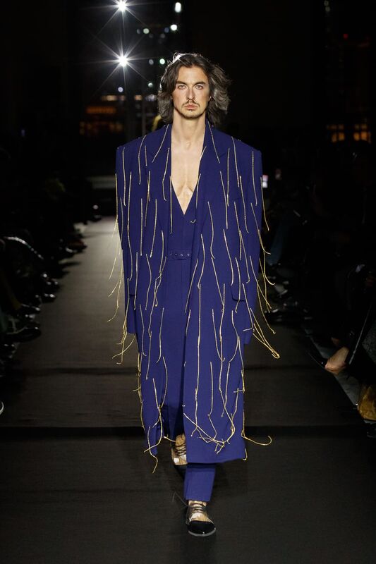 Яркий синий костюм с объемными плечами и золотыми деталями, подчеркивающий мужественность и стиль