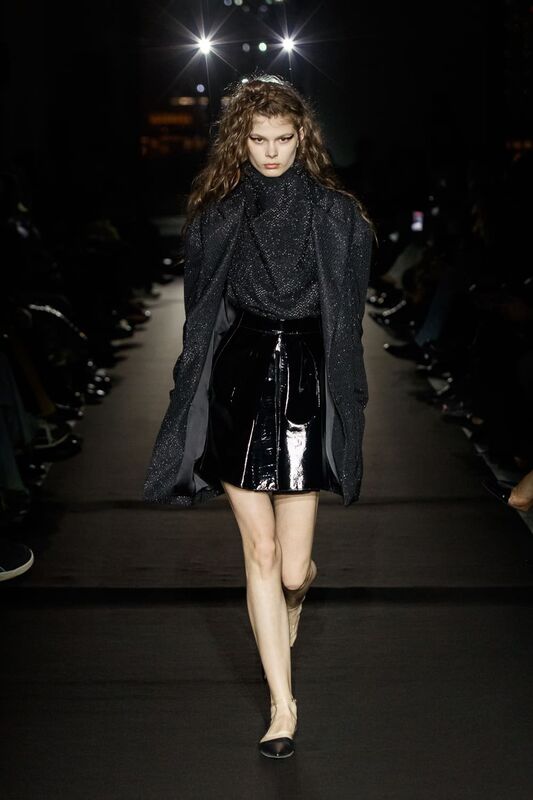 Блестящий черный топ с юбкой из лакированной кожи, создающий контраст между текстурами и отражениями света