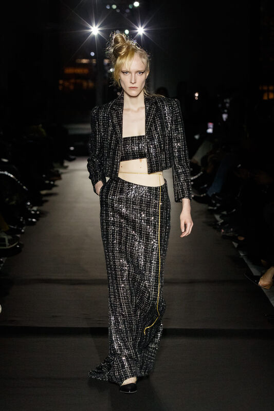 Блестящий черный костюм с укороченным жакетом и юбкой, подчеркивающий силуэт, излучает элегантность и современность.