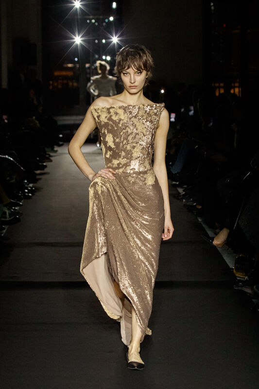 Платье с асимметричным кроем в золотистых тонах, украшенное пайетками, создает роскошный и утонченный вид.