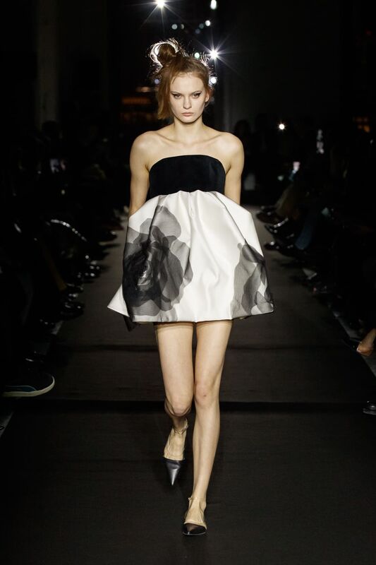 Минималистичное платье с черным корсетом и объемной юбкой, украшенной полупрозрачными цветами, создает игривый образ