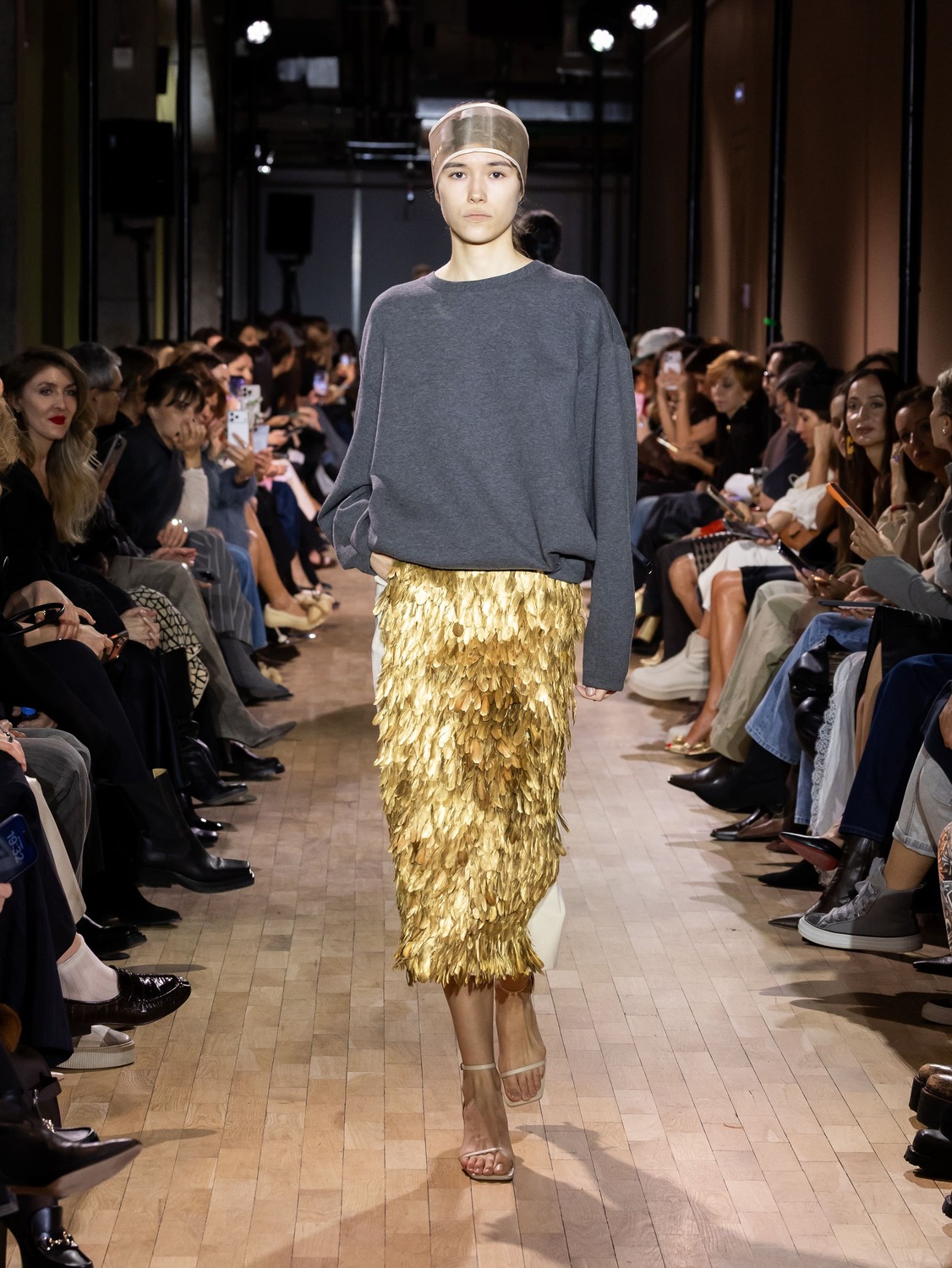 Серый свитер в сочетании с золотой юбкой из перьев создает эффектный контраст, подчеркивая элегантность образа