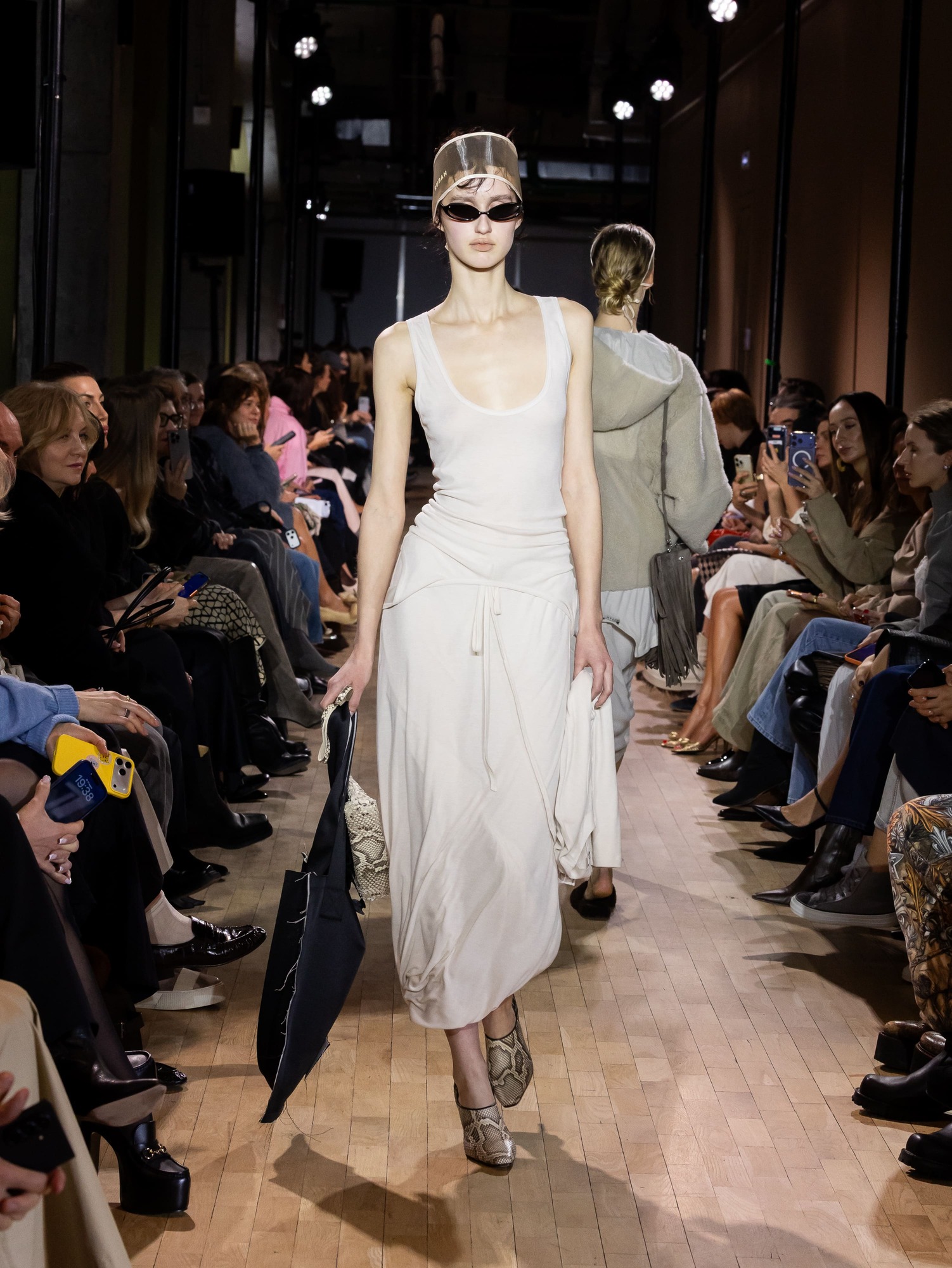 Элегантное белое платье с драпировкой, дополненное стильными солнцезащитными очками и сумкой, подчеркивающее утонченность