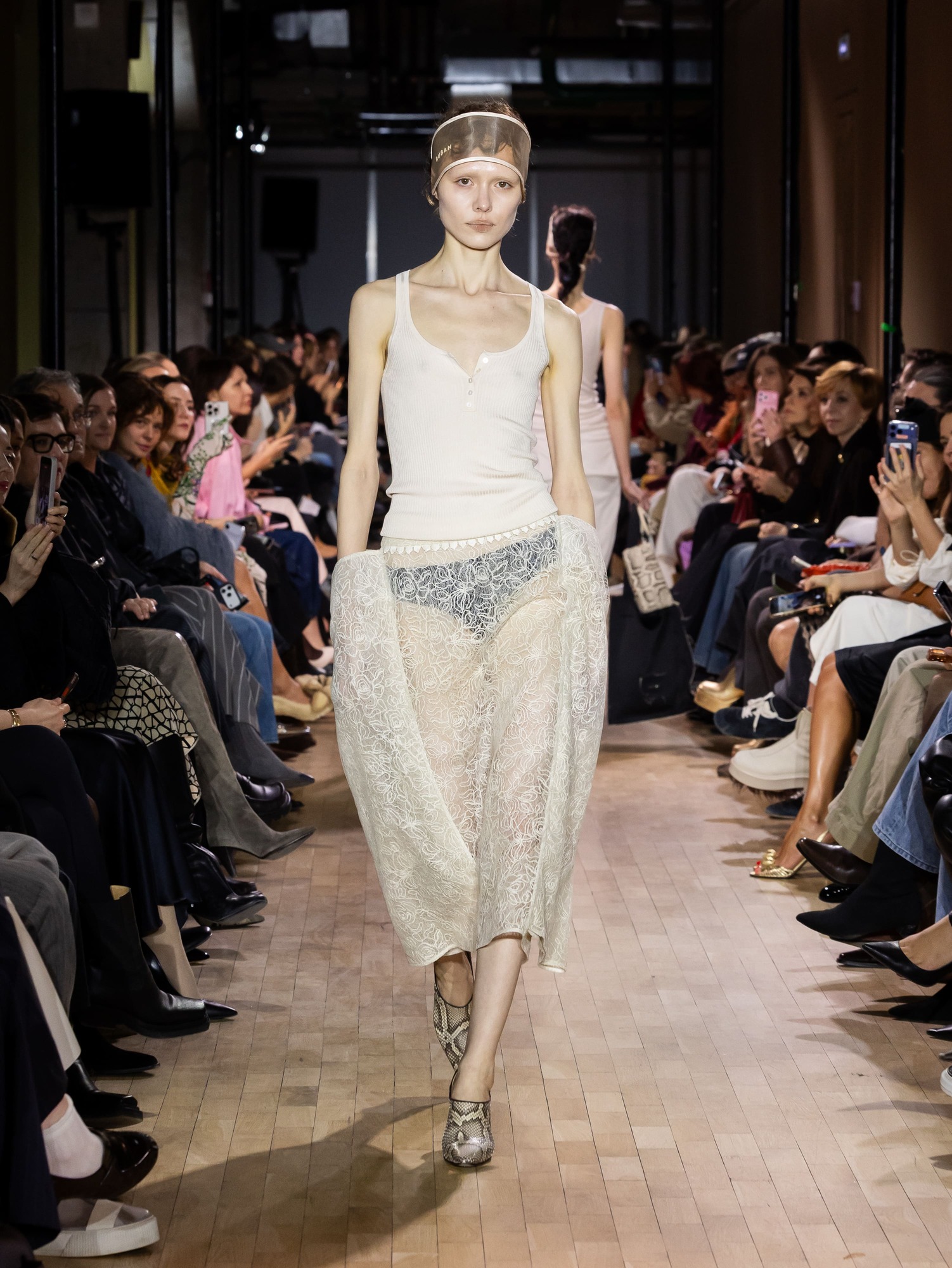 Модель в белом топе и кружевной юбке, изящно подчеркивающей силуэт, с акцентом на обувь в змеиный принт