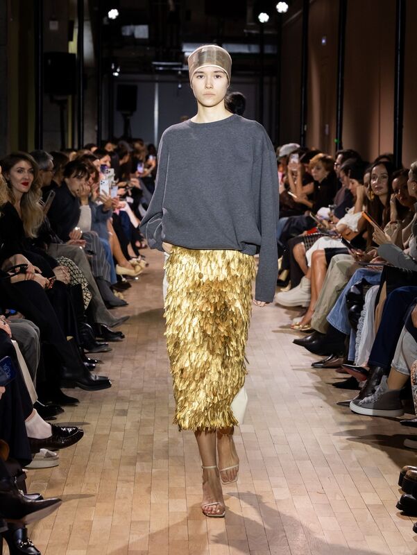 Серый свитер в сочетании с золотой юбкой из перьев создает эффектный контраст, подчеркивая элегантность образа