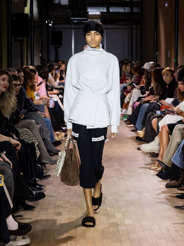 Спортивный стиль с серым свитером и черными брюками, акцент на удобство и современность, завершает образ сумка в руках