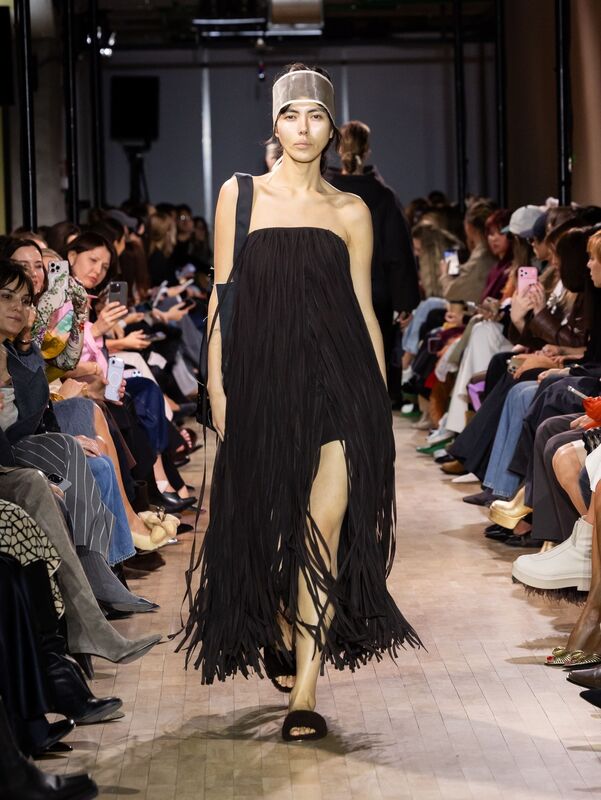 Элегантное черное платье с бахромой, открывающее ноги, подчеркивающее силуэт, с акцентом на минимализм