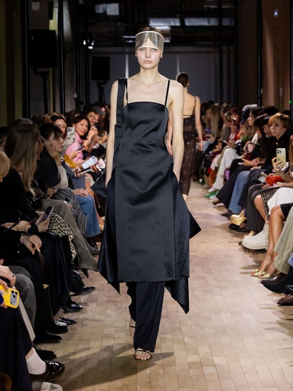 Строгое черное платье с асимметричным подолом, дополненное брюками, создающее эффектный контраст