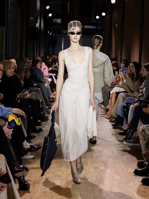 Элегантное белое платье с драпировкой, дополненное стильными солнцезащитными очками и сумкой, подчеркивающее утонченность