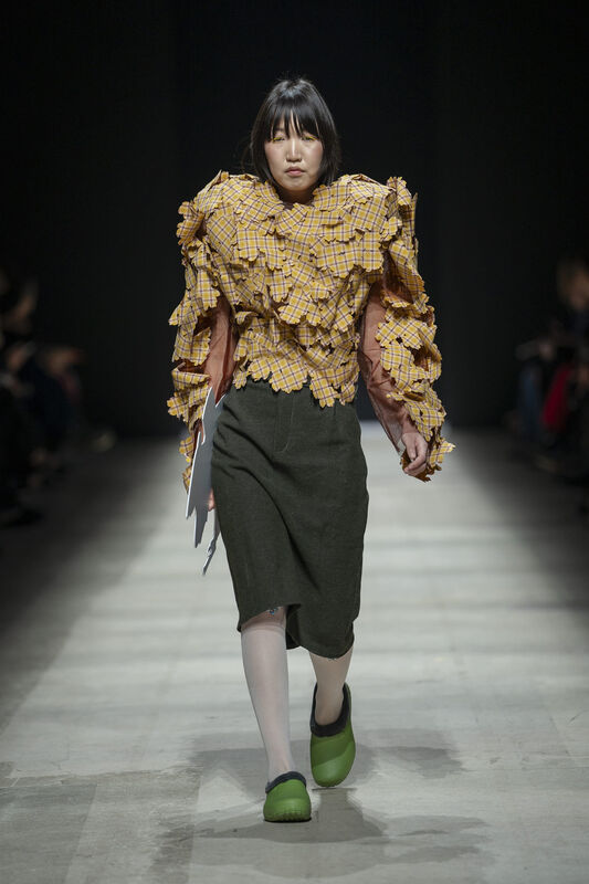 Объемный жакет в клетку с рифленой текстурой и асимметричная юбка в сочетании с яркими зелеными сабо создают уникальный образ.