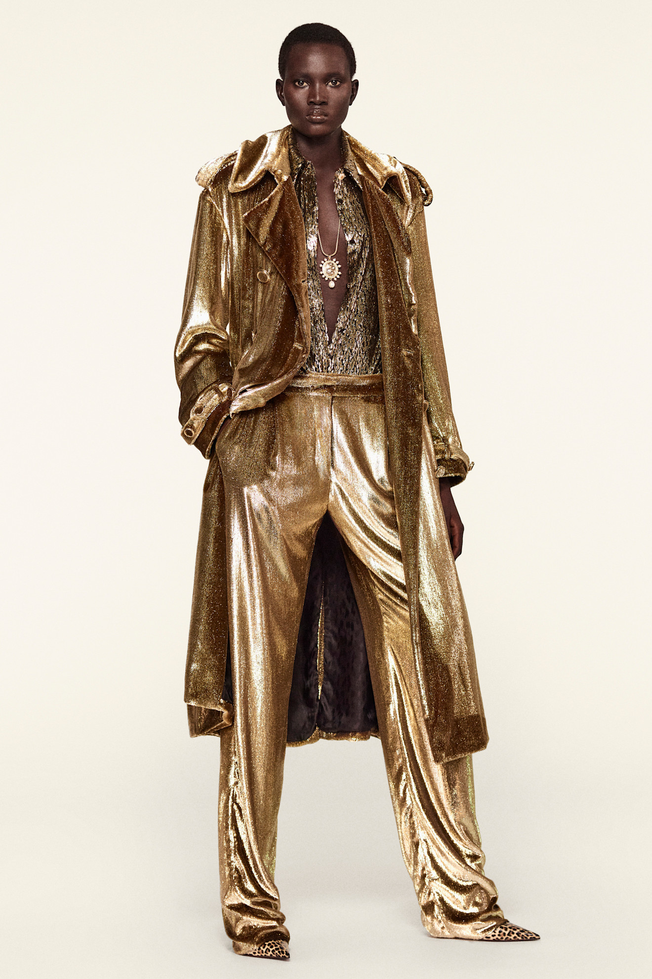 Золотистый костюм с блестящей текстурой и длинным плащом, создающий эффект роскоши и уверенности