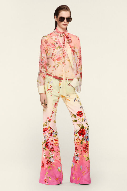 Полупрозрачная блуза с цветочным принтом и расклешенные брюки, создающие романтичный и стильный образ для весны