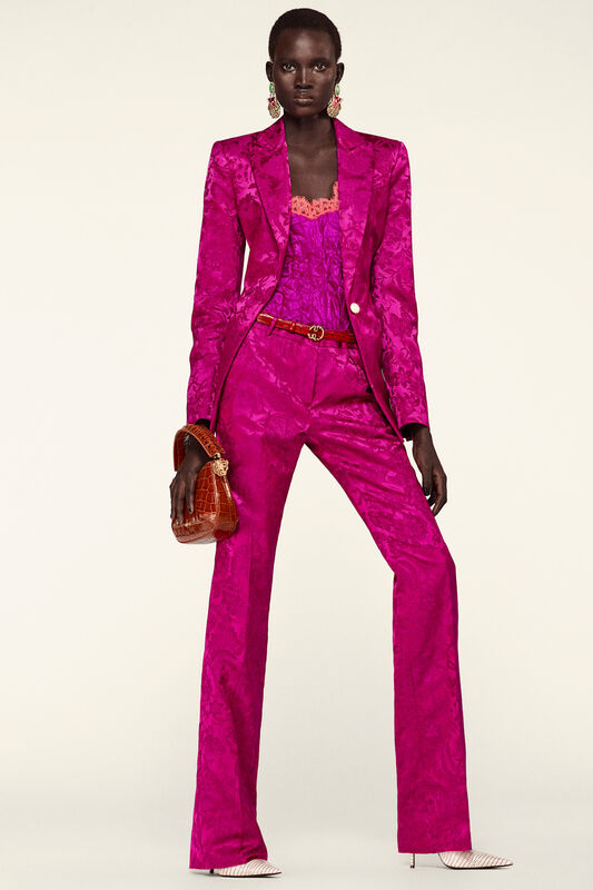 Яркий розовый костюм с узором, дополненный кружевным топом и стильной сумкой, создает эффектный образ для Resort 2026